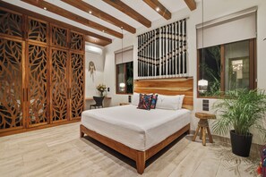 Een moderne slaapkamer met een houten hoofdbord, een groot bed, een decoratief wandpaneel, een klein nachtkastje en een pot met een plant.