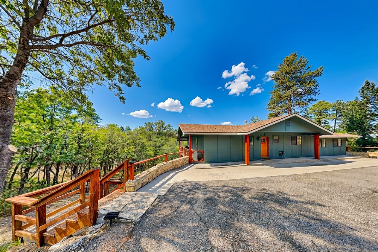 A building with a porch, a wooden fence, and a gravel driveway.