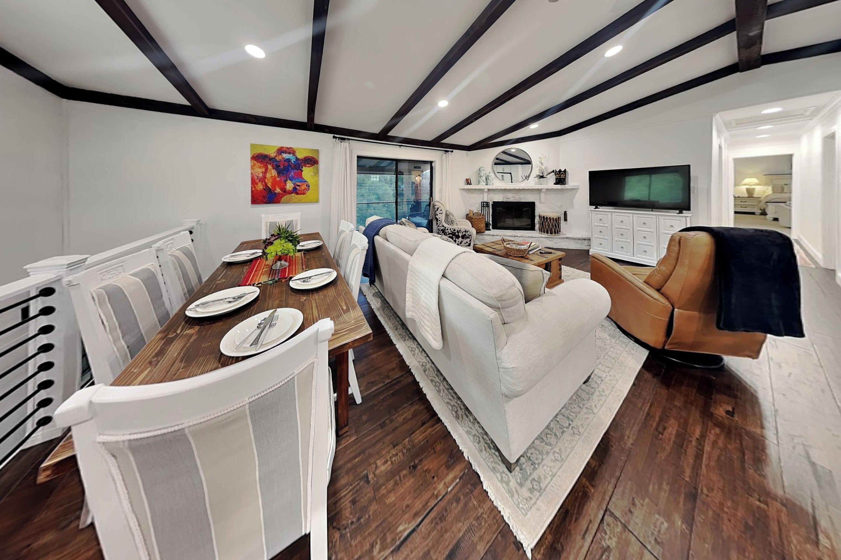 A modern living room with a dining area, a fireplace, and a television.