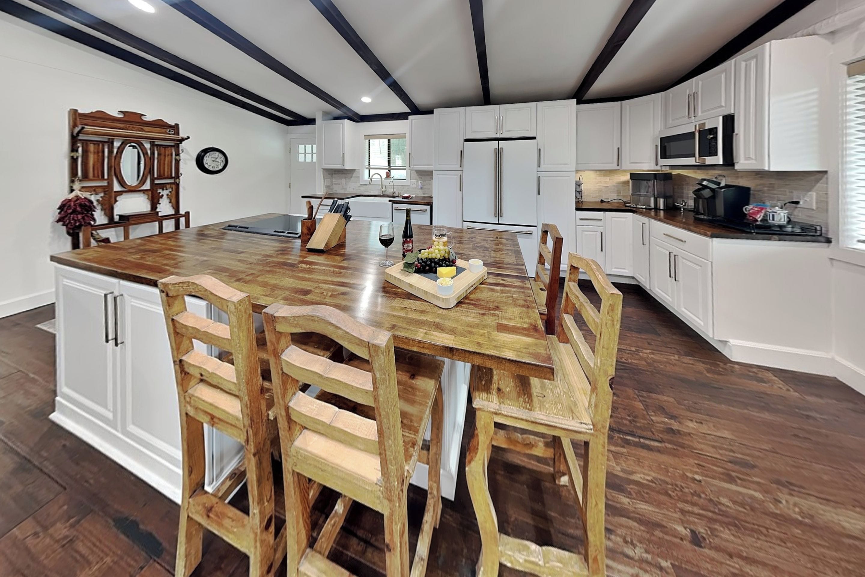 A spacious kitchen with white cabinetry, a wooden island with bar stools, and a built-in oven.