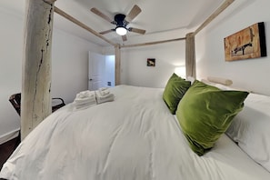 A bedroom with a bed, pillows, a ceiling fan, and a painting on the wall. - Amigos Nest (Alto)