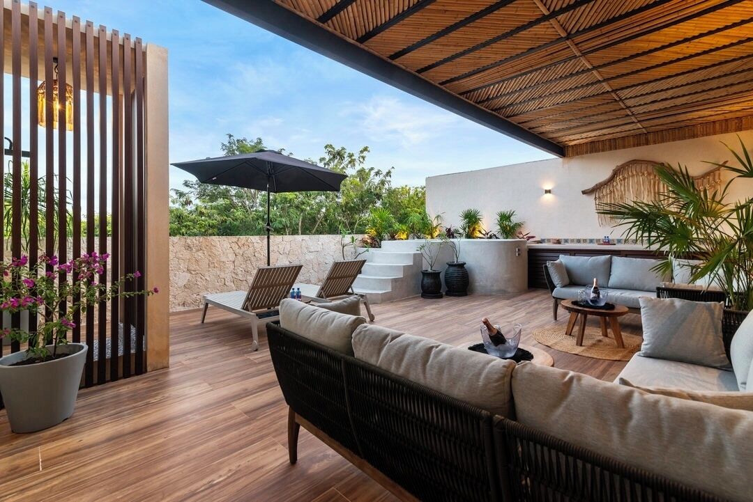 Un patio al aire libre con techo de madera, mobiliario de mimbre y plantas en macetas.