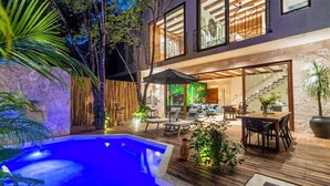 Ein modernes Haus mit Swimmingpool, Gartenmöbeln und einer Treppe, die zu der oberen Etage führt.
