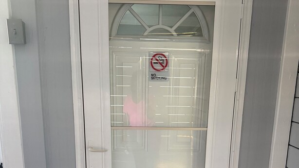 Een witte deur met een geëtste glazen ruit en een ‘Niet roken’-bord.