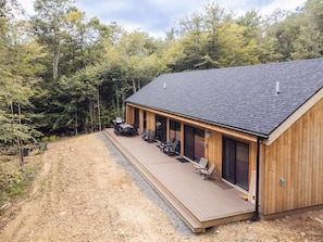 Una cabaña de madera con terraza cubierta, rodeada de bosque.
