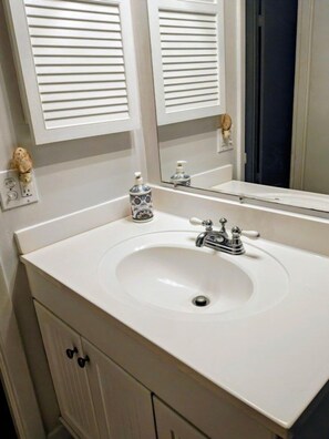 A bathroom with a white sink, two mirrors, and a cabinet with a single drawer. - Complex With Lots of Amenities and Across the street from Beach (Daytona Beach)