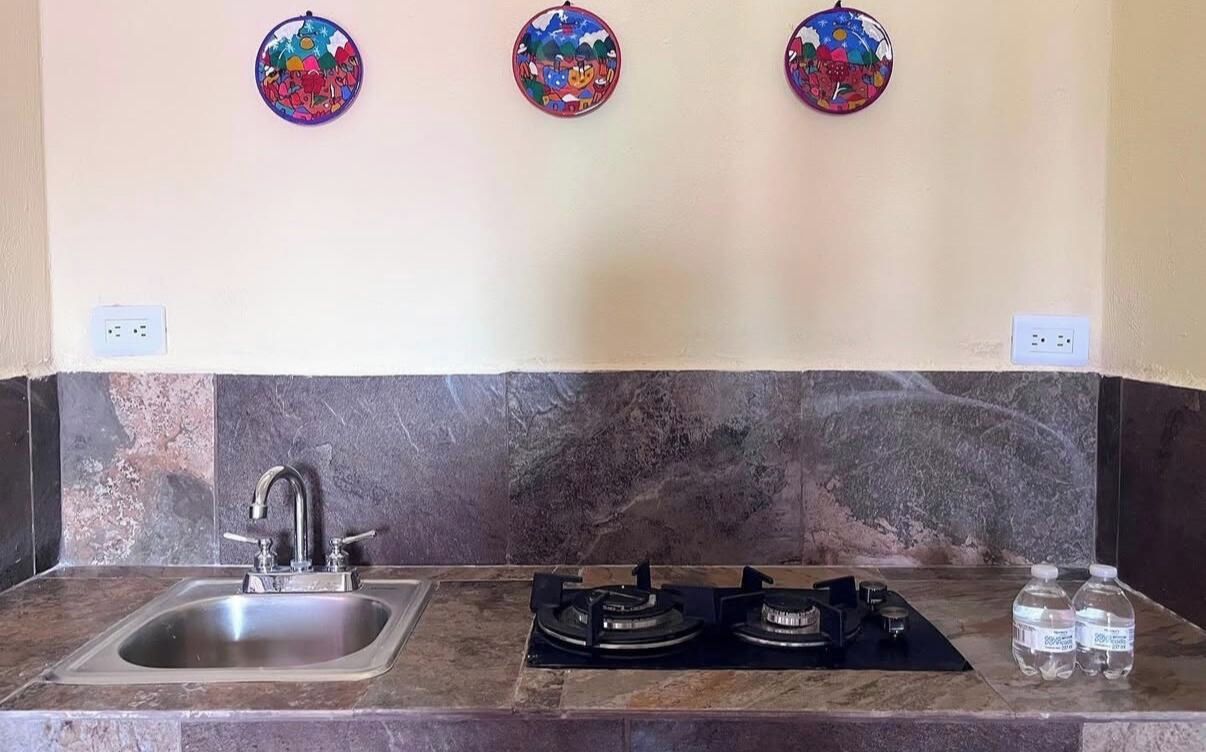 Cozinha com pia, fogão e arte decorativa na parede.