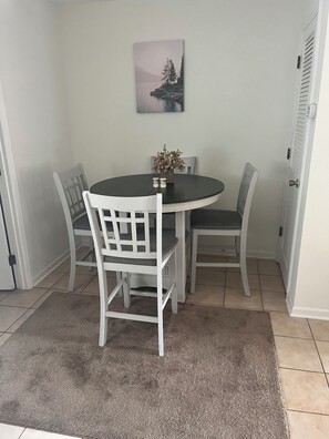 Un'area pranzo con un tavolo rotondo, quattro sedie, una piccola pianta in vaso e un quadro appeso al muro.