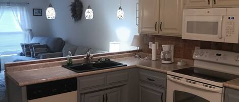 A kitchen with white cabinets, a dishwasher, a stove, and a microwave.