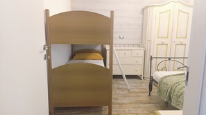 Una habitación con literas, un aparador blanco y un armario.