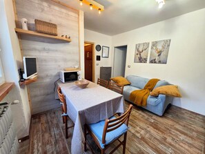 A dining area with a table, chairs, a microwave, and a television on a shelf. - Casa della Marmotta by Ca-sa Check (Aprica)