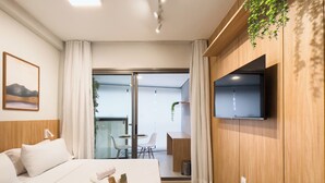 A hotel room with a bed, a TV mounted on the wall, a dining table with chairs, and a sliding glass door leading to a balcony. - ON Vila Madalena (São Paulo)