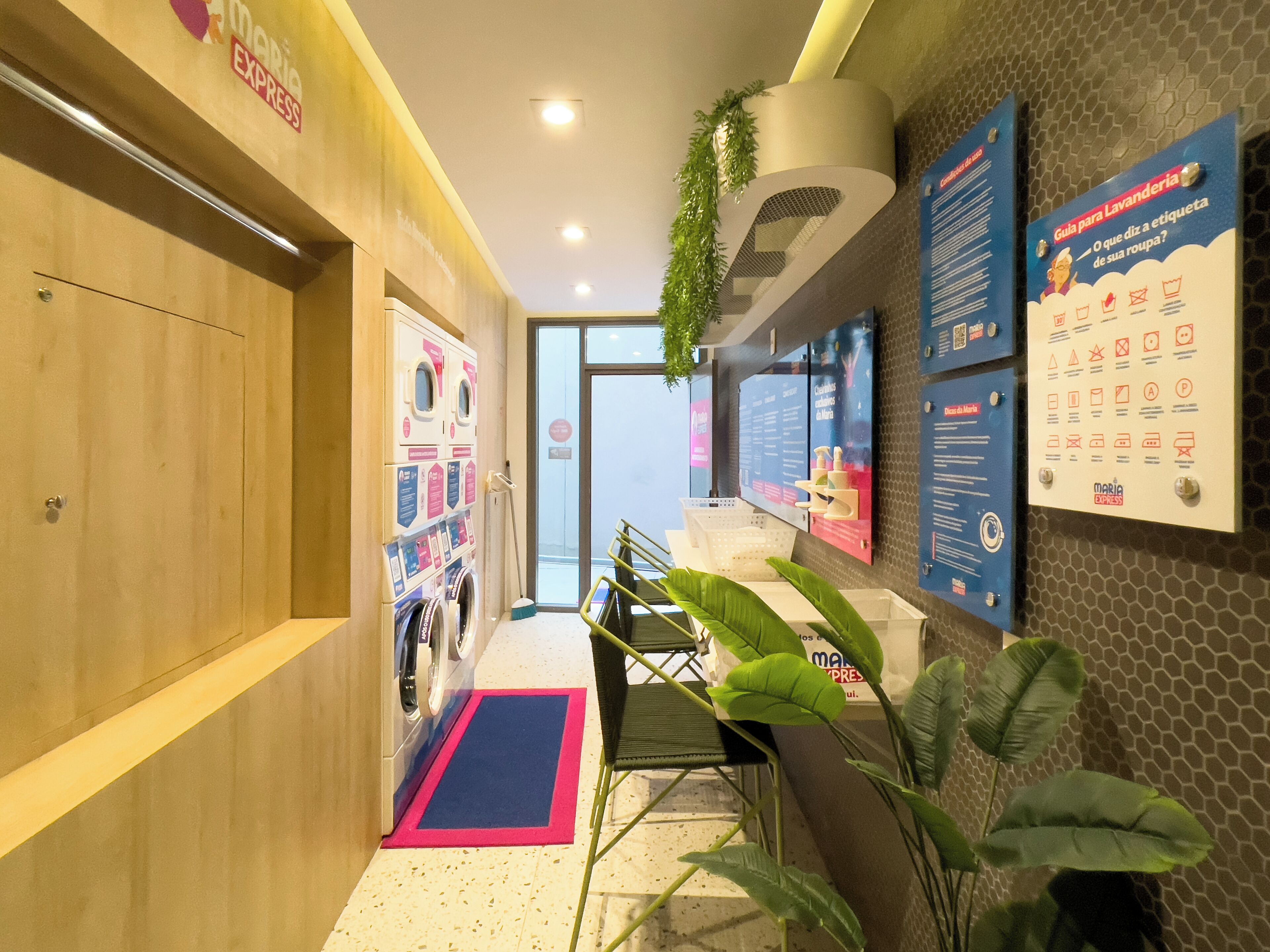 Un vestíbulo de hotel con una recepción, un panel informativo en la pared y una planta.