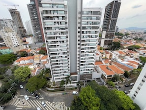 Ein Hochhaus mit mehreren Balkonen, umgeben von einer Mischung aus Wohn- und Geschäftsgebäuden.