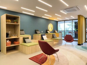 Un espace d’attente moderne, doté de sièges, d’un panneau lumineux au néon et offrant une vue sur l’extérieur grâce à de grandes fenêtres.