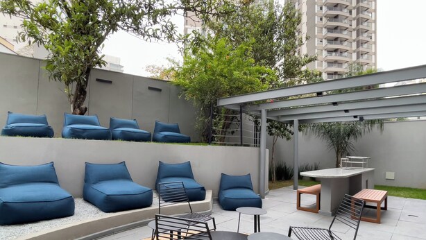 An outdoor seating area with blue cushioned sofas and metal tables. - ON Vila Madalena (São Paulo)