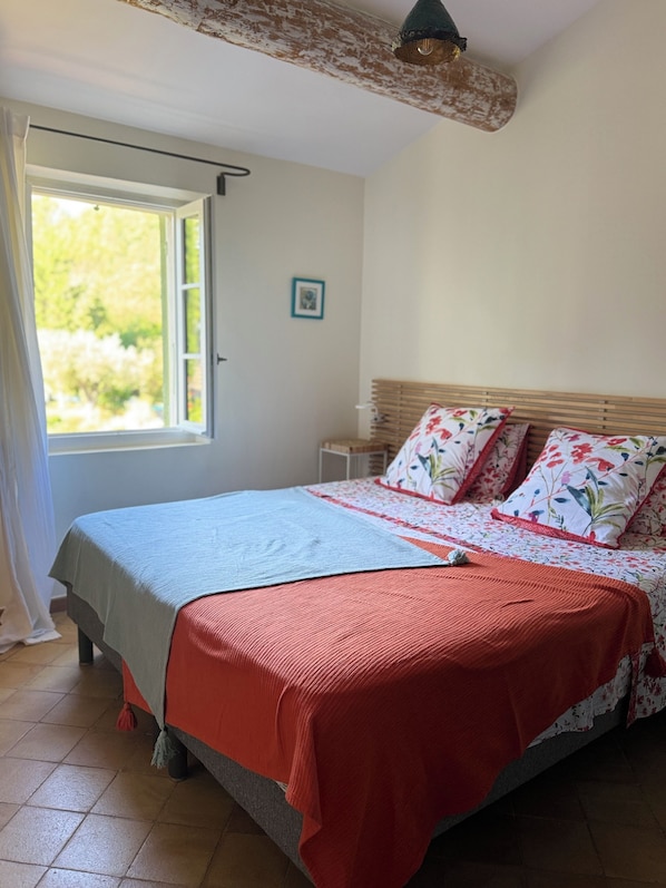 A bedroom with a bed, a window, and a door.