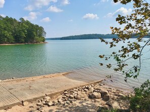 A calm lake with a sandy beach and rocky shoreline.