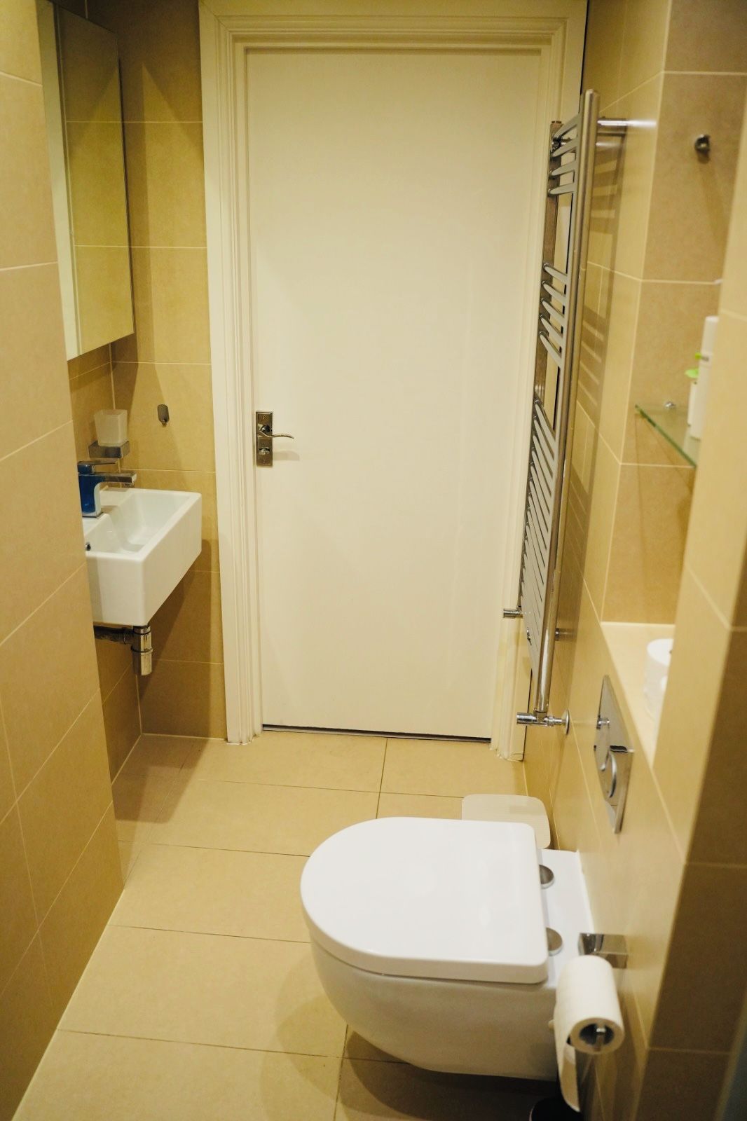Une petite salle de bain avec des toilettes blanches, un lavabo et un espace douche.