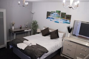 Quarto de hotel bem organizado, com cama, mesa de cabeceira, abajur e espelho.