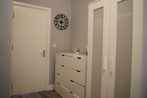 Ein Korridor mit einer weißen Tür, einer Wanduhr und einem Schrank mit mehreren Schubladen.