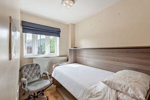 A bedroom with a bed, a chair, a window with a view of greenery, and a radiator. - Host & Stay | Thornbank (Chichester)
