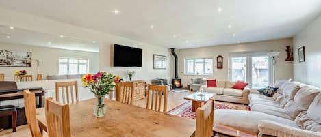Amplia sala de estar con una mesa de comedor de madera, sofás y una chimenea.