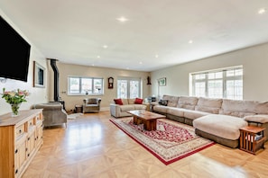 A spacious living room with a large sofa set, a wooden cabinet, and a fireplace. - Host & Stay | Thornbank (Chichester)