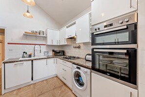 Eine moderne Küche mit weißen Schränken, einem Einbauofen, einer Mikrowelle und einer Waschmaschine.