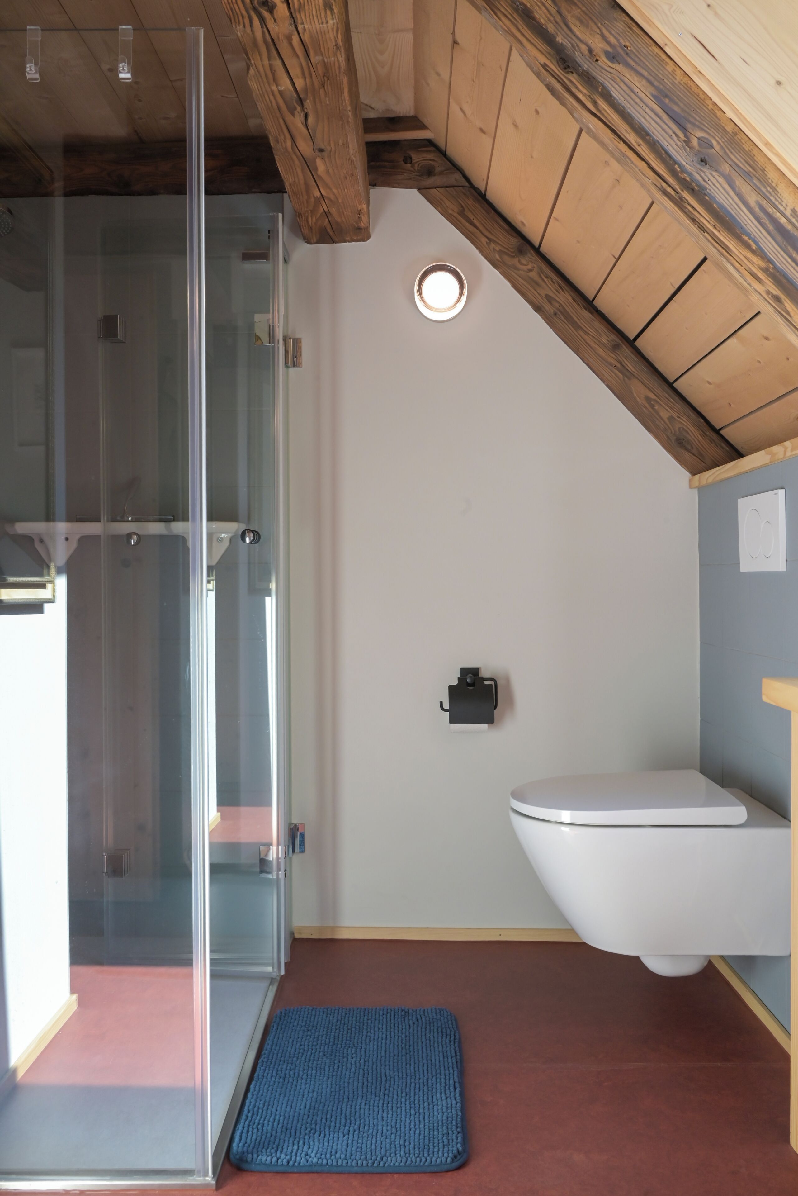Ein Badezimmer mit Duschkabine aus Glas, Toilette und Waschbecken.
