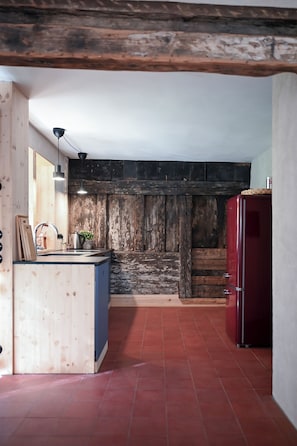 A kitchen with a wooden wall, a sink, a stove, and a refrigerator.