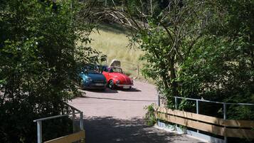 Una strada asfaltata che conduce a un’area di parcheggio con due auto.