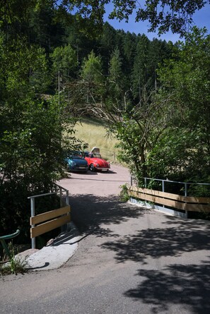 A paved road leading to a parking area with two cars parked.