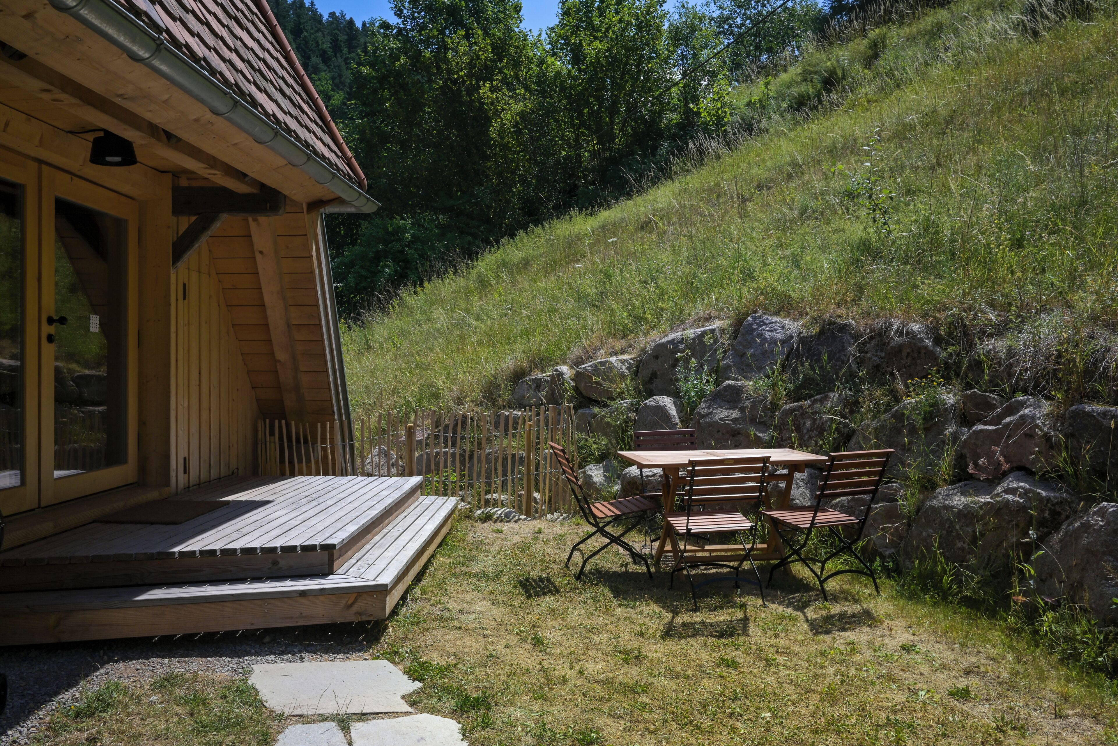 Une cabane en bois avec une véranda, une table et des chaises à l’extérieur.