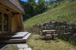 Una cabana de fusta amb un porxo, una taula i cadires a l'exterior.
