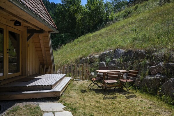 A wooden cabin with a porch, a table, and chairs outside.
