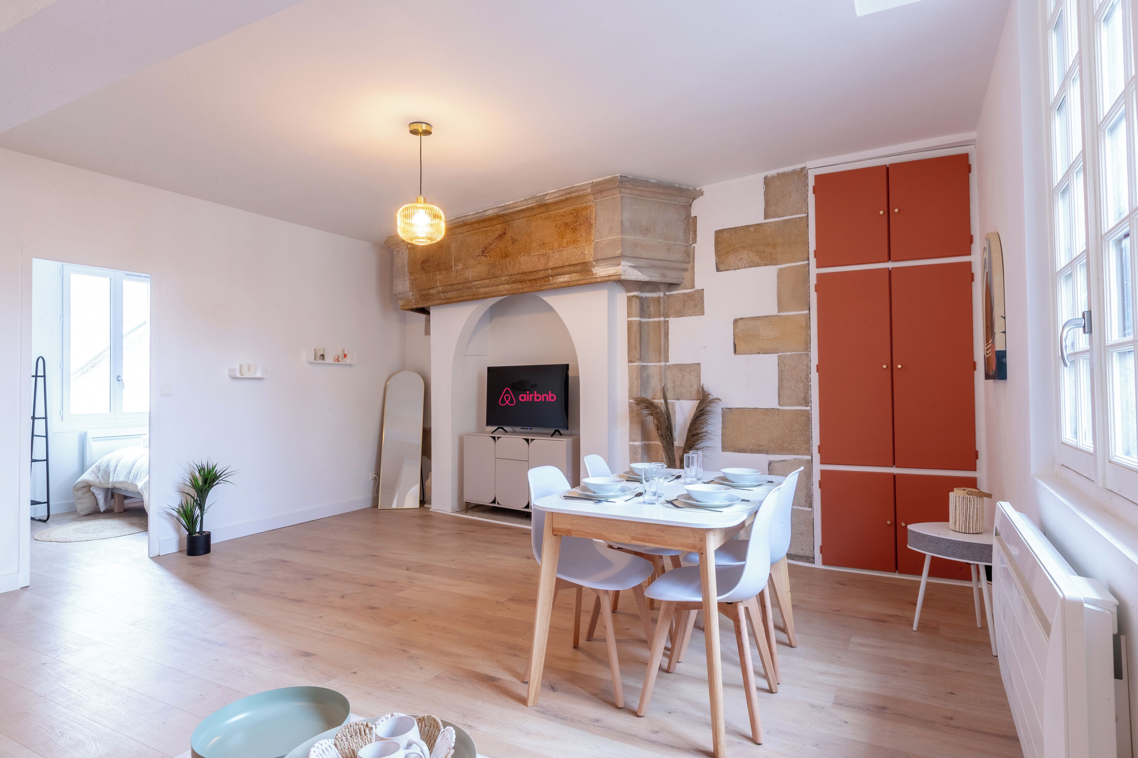 Un comedor con una mesa y sillas de madera, televisor y chimenea de piedra.