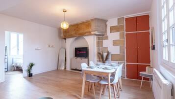 Un comedor con una mesa y sillas de madera, televisor y chimenea de piedra.