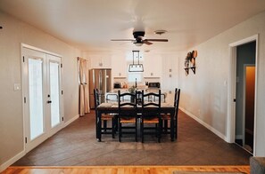 Una cocina amplia con una mesa y sillas de comedor, un ventilador de techo y un refrigerador.