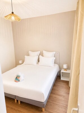 A hotel room with a bed, bedside tables, a lamp, and a hanging light fixture.