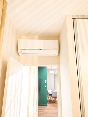 Ein Flur mit einer Decken-Klimaanlage, einer grünen Tür zu einem Essbereich und einer weißen Wand.
