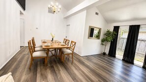A dining area with a wooden table and chairs, a chandelier, and a potted plant. - Spacious 4-bedroom house in wonderful Spring with AC (Spring)