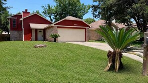 A residential property with a red garage, a brick house, and a well-maintained lawn. - Spacious 4-bedroom house in wonderful Spring with AC (Spring)