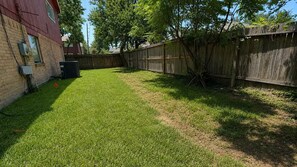 A backyard with a wooden fence, a brick house, and a tree. - Spacious 4-bedroom house in wonderful Spring with AC (Spring)