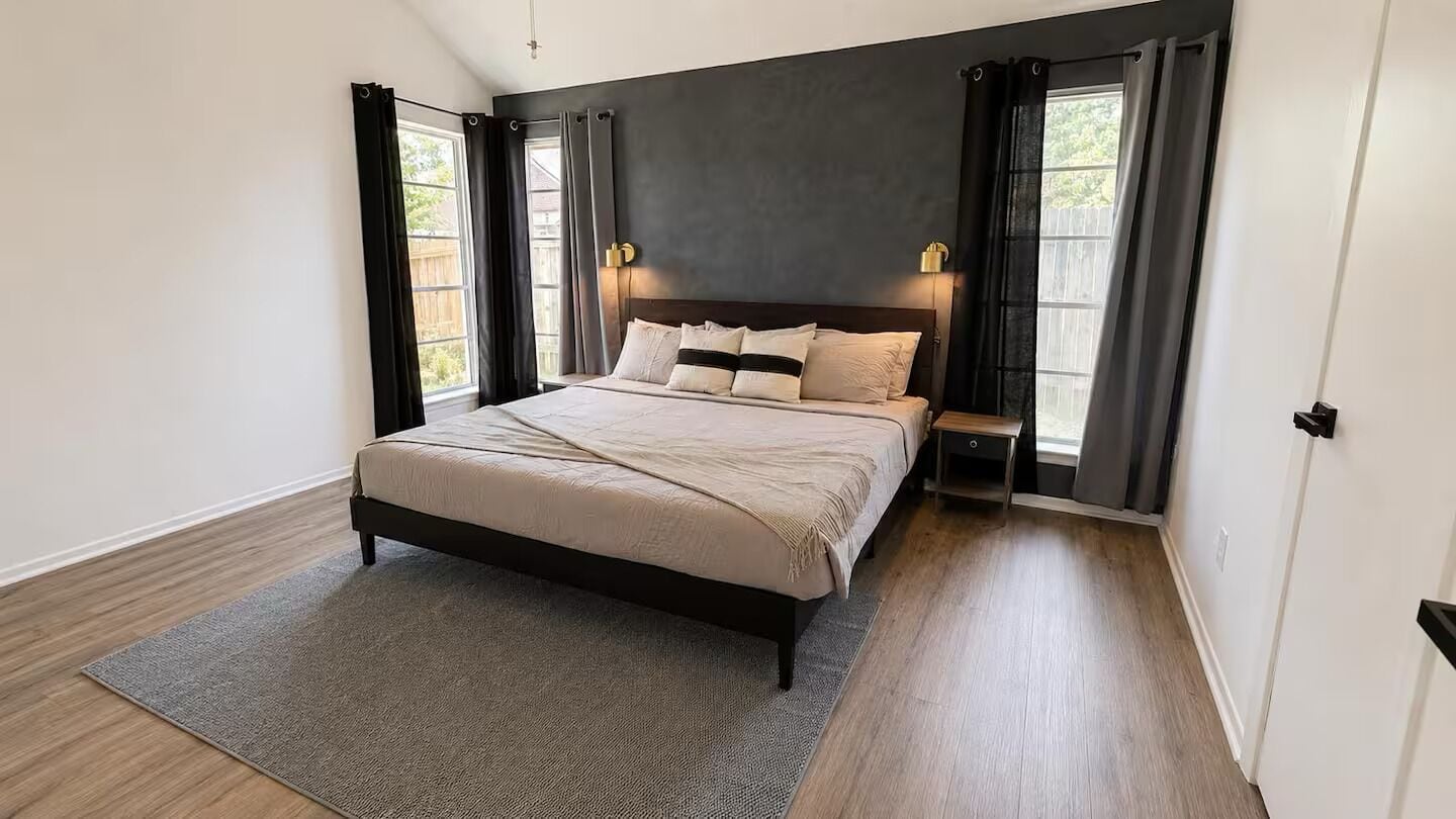Een slaapkamer met een bed, nachtkastje en een raam met gordijnen.