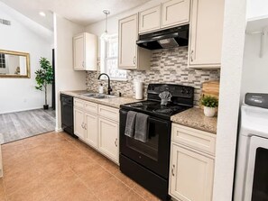 A kitchen with a black stove, white cabinets, a tiled backsplash, and a Samsung refrigerator. - Spacious 4-bedroom house in wonderful Spring with AC (Spring)