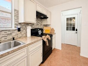 A kitchen with white cabinets, a black stove, and a window with a view of a building. - Spacious 4-bedroom house in wonderful Spring with AC (Spring)