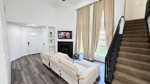 A living room with a sofa, a fireplace, a television, and a staircase. - Spacious 4-bedroom house in wonderful Spring with AC (Spring)