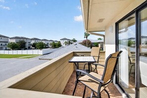 A balcony with a table and chairs, overlooking a street and neighboring buildings. - Stay Coastal. Stay Coconut / Closer to the beach. (Miramar Beach)