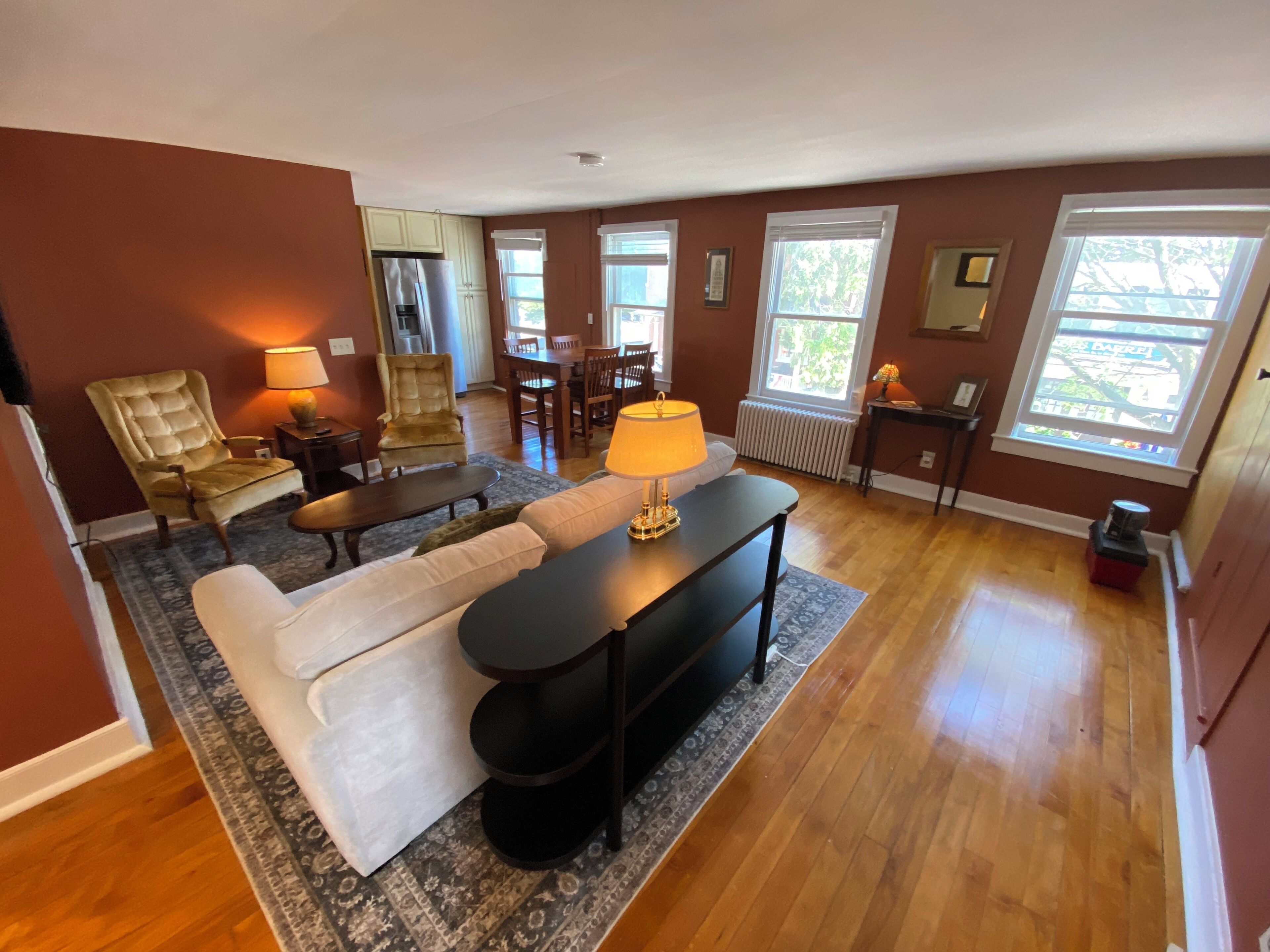 A living room with a sofa, armchairs, a coffee table, and a dining area with chairs and a table.